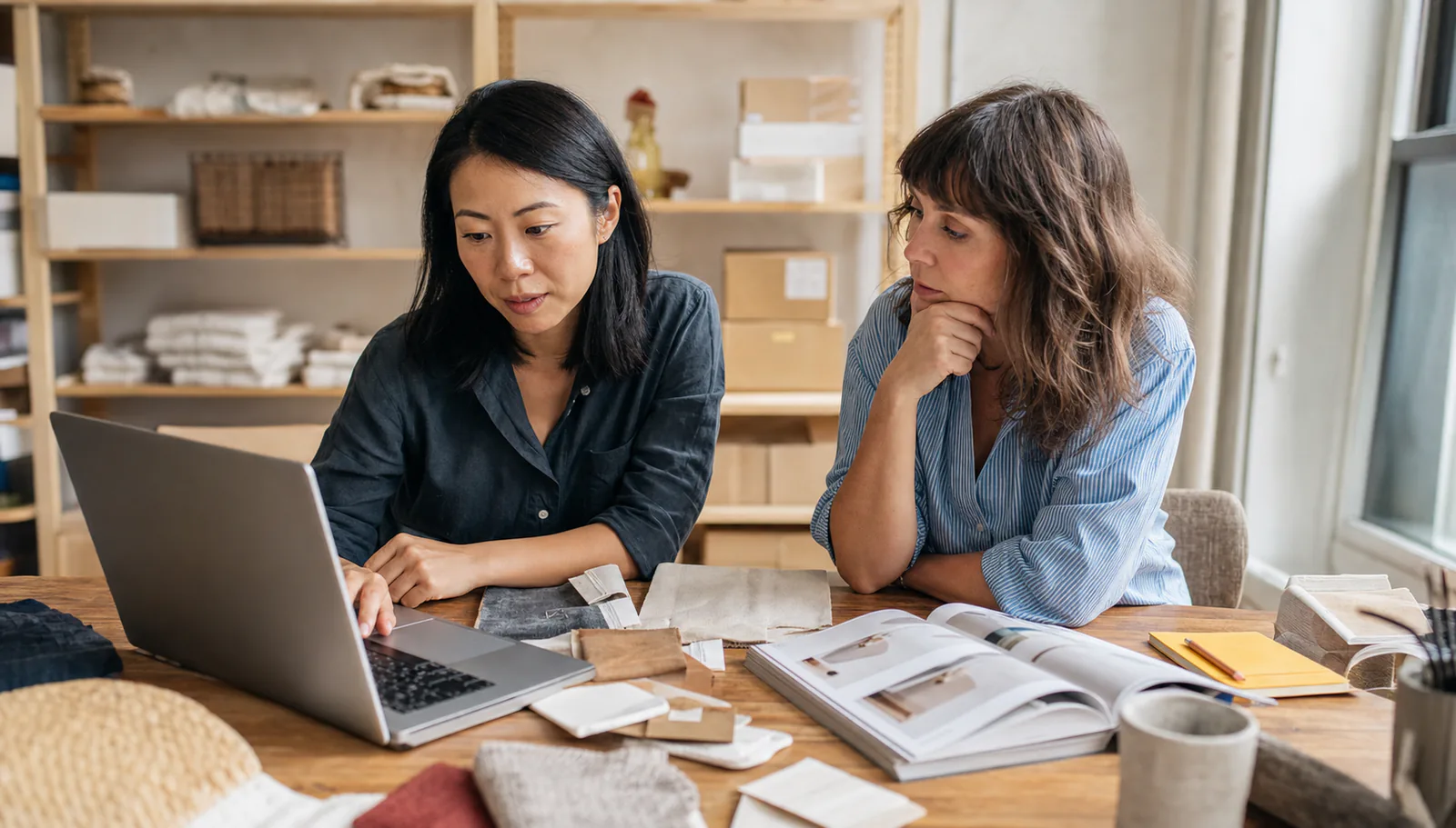 Two ecommerce specialists reviewing products and a digital catalog together.